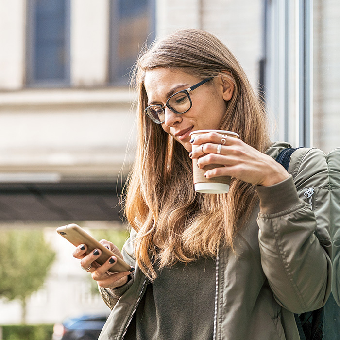 Woman drinking coffee and checking her phone