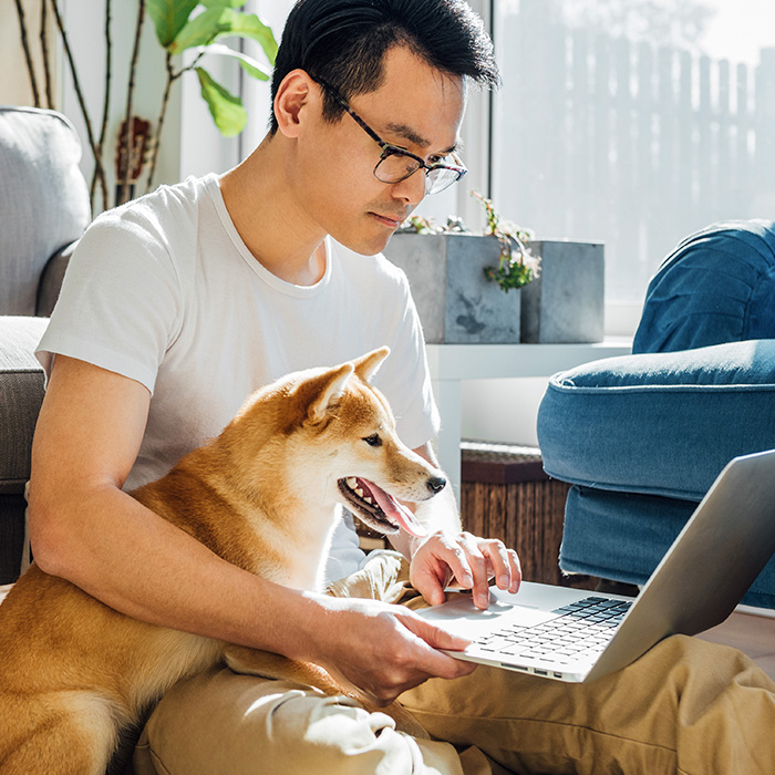 Man with dog on lap and laptop