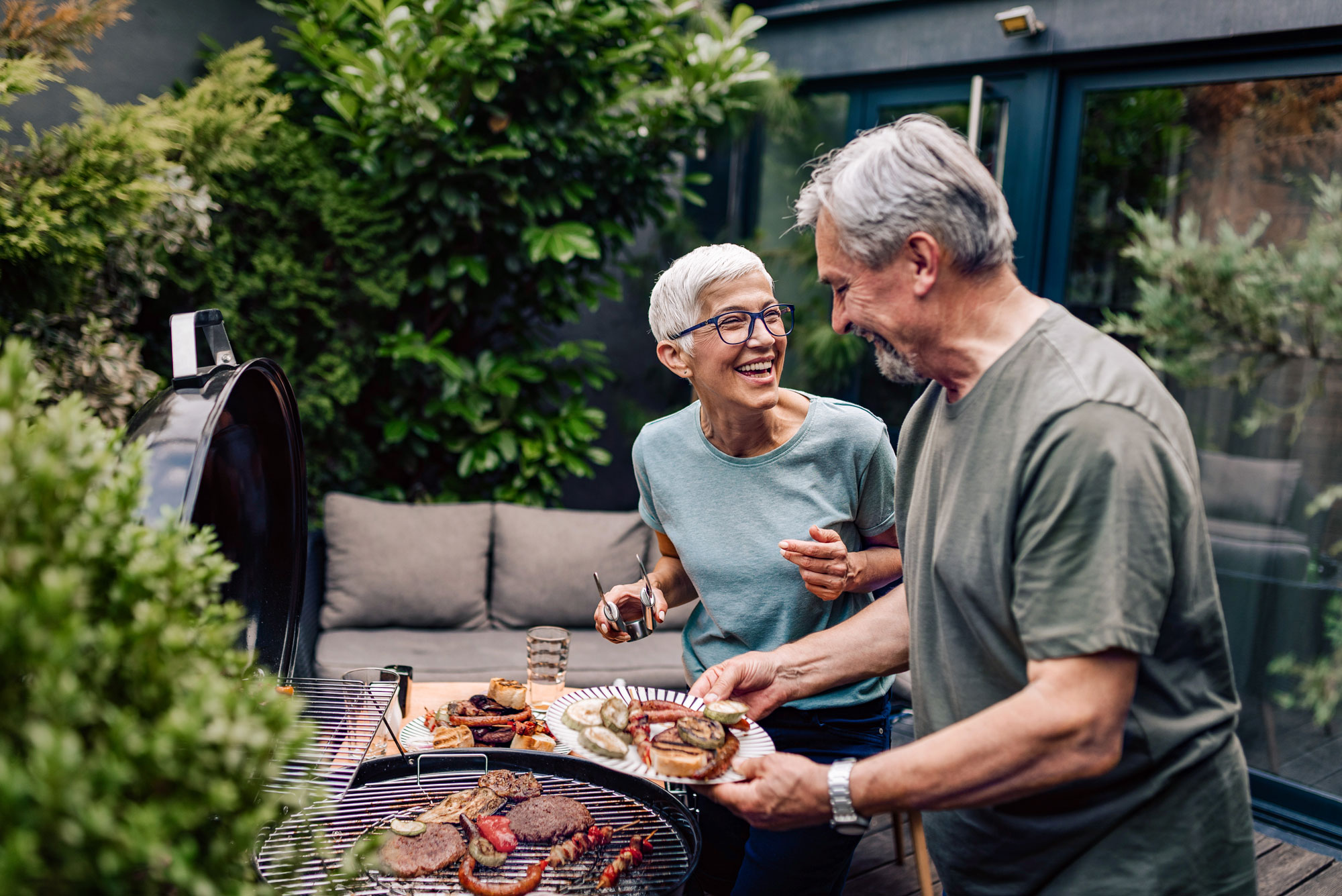 Senior couple grilling together outside